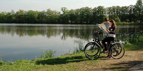 fietsers plannen hun fietstocht op de fietskaart van Limburg langs een vijver